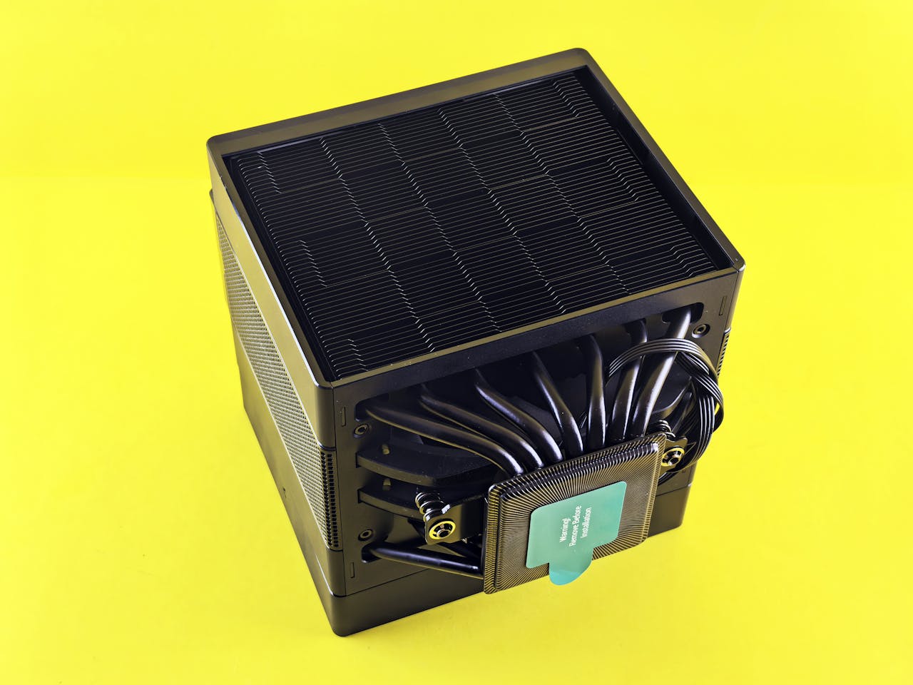Black CPU cooler with intricate design showcased on a vibrant yellow background, emphasizing cooling technology.